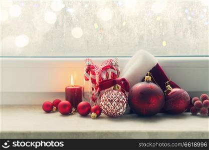 Christmas styled scene with glowing candle and christmas decorations on winter windowsill, retro toned. Christmas scene with burning light