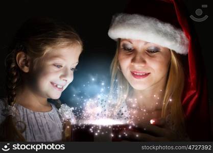 Christmas surprise. Happy daughter receiving Christmas gift from mother