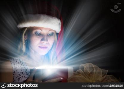 Christmas surprise. Happy woman in santa hat opening Christmas gift box