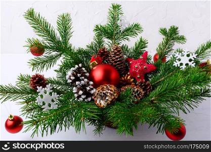 Christmas table centerpiece with red balls and hand decorated pine cones. Christmas decoration with fir branches and red baubles. Christmas greenery with ornaments in wicker basket.