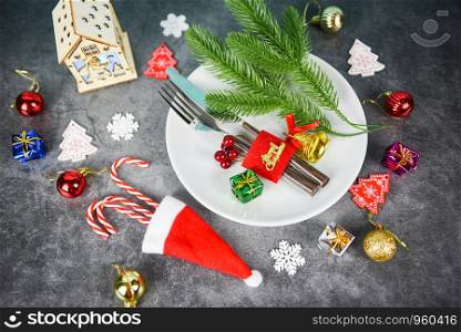 Christmas table place setting decoration with gift box ball candy cane in santa claus hat fork and knife on plate Xmas New Year food lunch festive Christmas dinner holidays background themed party