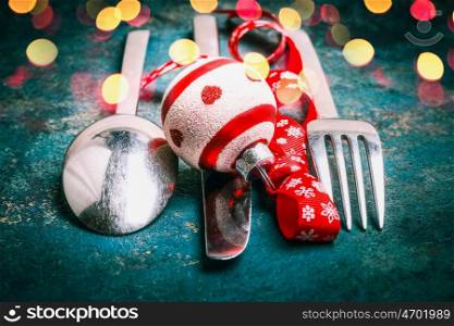 Christmas table place setting with cutlery , holiday decoration and bokeh, front view, close up