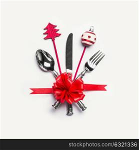 Christmas table place setting with cutlery, red ribbon and minimal decoration on white desk background, top view. Layout for holiday greeting card, festive dinner invitation