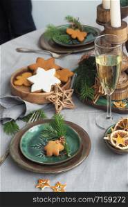 Christmas table setting. ceramic plates, fir branches, gingerbread, vintage cutlery, candles in candlesticks, dry orange slices.