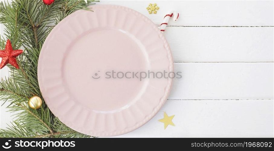 Christmas table setting. empty pink plate fir branches, snowflakes and stars. copy space.