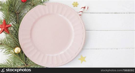 Christmas table setting. empty pink plate fir branches, snowflakes and stars. copy space.