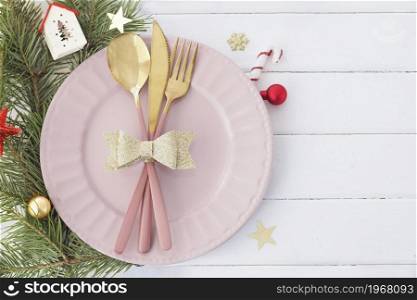 Christmas table setting in white-pink-gold colors. pink plate, cutlery with gold bow, fir branches, snowflakes and stars. Copy space.