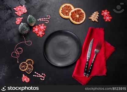 Christmas table setting with empty black ceramic plate, fir tree branch and black accessories on black stone background. Christmas table setting with empty black ceramic plate, fir tree and black accessories