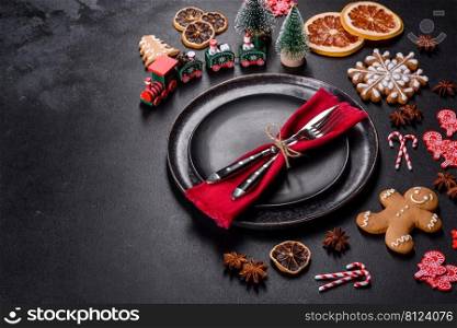 Christmas table setting with empty black ceramic plate, fir tree branch and black accessories on black stone background. Christmas table setting with empty black ceramic plate, fir tree and black accessories