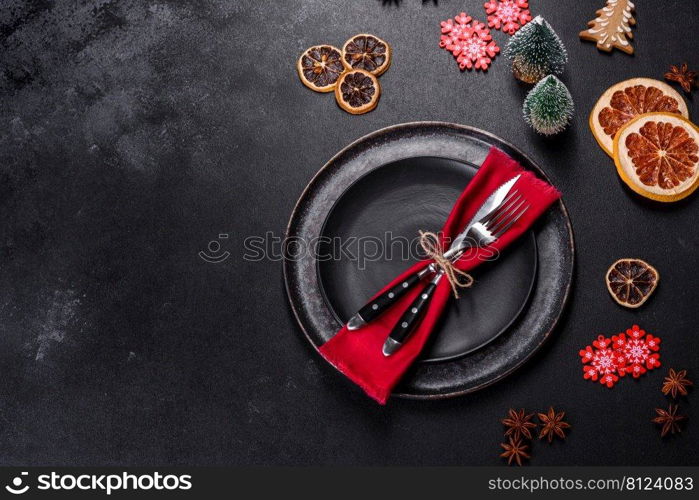 Christmas table setting with empty black ceramic plate, fir tree branch and black accessories on black stone background. Christmas table setting with empty black ceramic plate, fir tree and black accessories