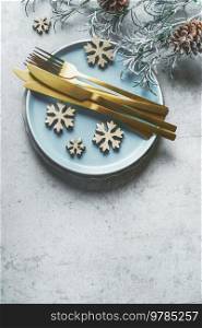 Christmas table setting with golden cutlery , blue plate and snowflakes decoration , top view