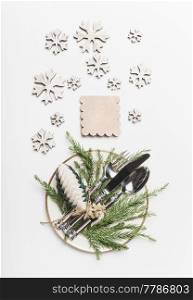 Christmas table setting with plates, cutlery , fir branches snowflakes and tags on white background, top view, flat lay. Holiday concept