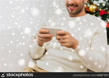 christmas, technology, people and holidays concept - close up of smiling man with smartphone at home