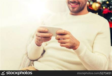 christmas, technology, people and holidays concept - close up of smiling man with smartphone at home. smiling man with smartphone at home for christmas
