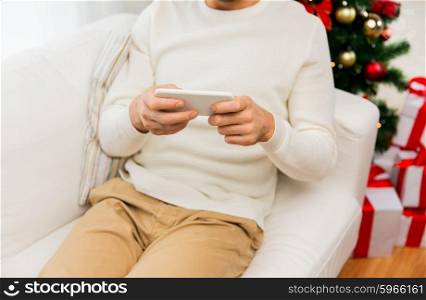 christmas, technology, people and holidays concept - close up of smiling man with smartphone at home