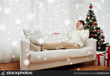 christmas, technology, people and holidays concept - smiling man calling on smartphone at home