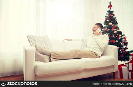 christmas, technology, people and holidays concept - smiling man calling on smartphone at home. man calling on smartphone at home for christmas