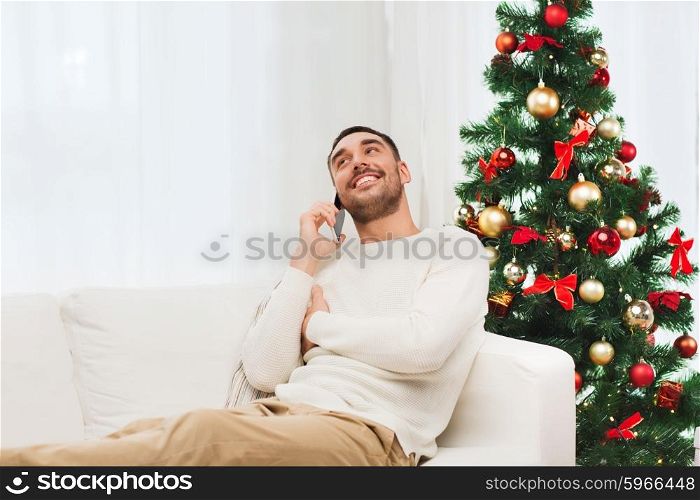 christmas, technology, people and holidays concept - smiling man calling on smartphone at home