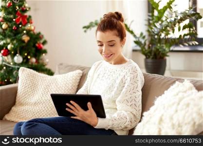 christmas, technology, people and holidays concept - smiling woman with tablet pc computer at home. woman with tablet pc at home on christmas