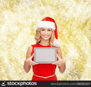 christmas, technology, present and people concept - smiling woman in santa helper hat with tablet pc computer showing blank screen over yellow lights background