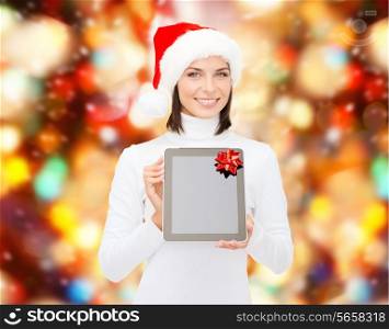 christmas, technology, present and people concept - smiling woman in santa helper hat with blank screen tablet pc computer over red lights background