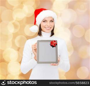 christmas, technology, present and people concept - smiling woman in santa helper hat with blank screen tablet pc computer over beige lights background