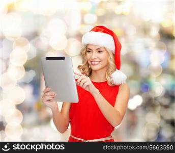 christmas, technology, present and people concept - smiling woman in santa helper hat with tablet pc computer over lights background