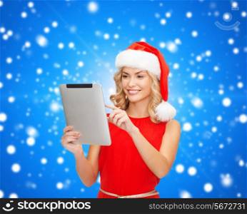 christmas, technology, present and people concept - smiling woman in santa helper hat with tablet pc computer over blue lights background