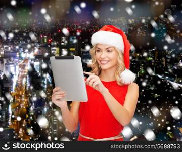christmas, technology, present and people concept - smiling woman in santa helper hat with tablet pc computer over snowy night city background