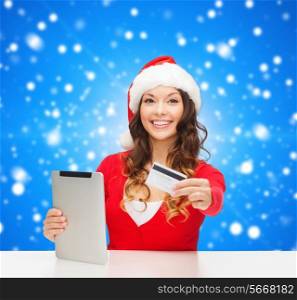 christmas, technology, shopping and people concept - smiling woman in santa helper hat with tablet pc computer and credit card over blue snowing background