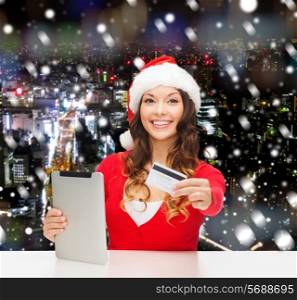 christmas, technology, shopping and people concept - smiling woman in santa helper hat with tablet pc computer and credit card over snowy night city background