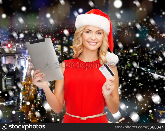 christmas, technology, shopping and people concept - smiling woman in santa helper hat with tablet pc computer and credit card over snowy night city background