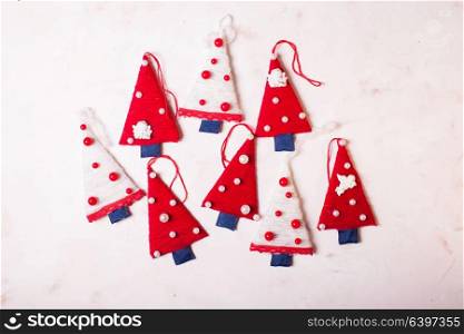 Christmas textile trees. Rag trees Christmas on pink marble surface, a branch of spruce in the corner