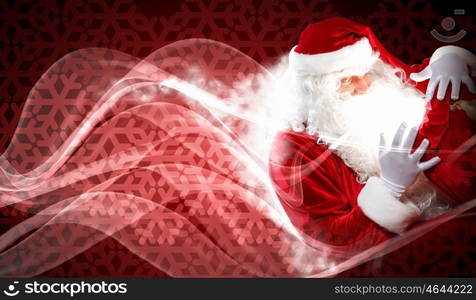 christmas theme with santa. Santa with beard and red hat holding and looking into the sack