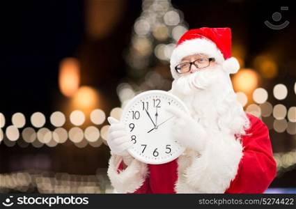 christmas time, holidays and people concept - santa claus with clock pointing finger to twelve. santa claus with clock pointing finger to twelve