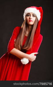 Christmas time. Young woman wearing santa claus hat red dress on black background. Studio shot.