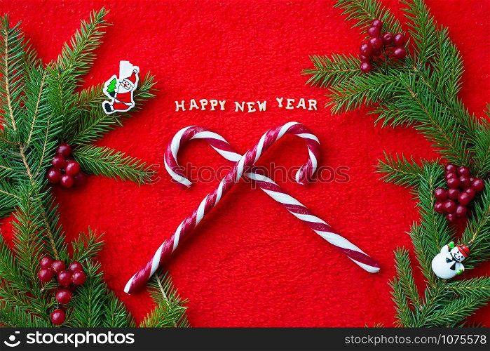Christmas tree and candy on a red background with the words Happy New Year. Closeup. Christmas tree and candy on a red background with the words Happy New Year