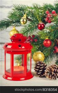 Christmas tree and decorative lantern with a candle. Red retro lantern, cone and balls and fir spruce branches on white brick background. Christmas tree and decorative lantern with a candle.