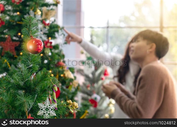 Christmas tree and ornament with background of young Teenager asian couple decorating Christmas tree together prepare for Christmas party holiday.
