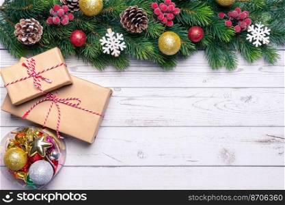 Christmas tree branch decorated with golden balls and gift box on white wooden background. Top view, flat lay with copy space, banner, header, New Year background