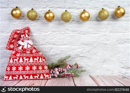 Christmas tree branch with decor and red gift bag with christmas pattern on white brick wall background. New Year background copy space, header, banner for site