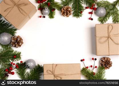Christmas tree branch with pine cones, red berries and gift boxes on white background with copy space. Christmas gift boxes and decor