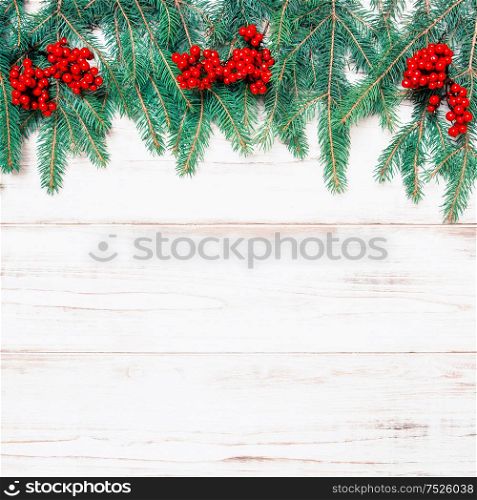Christmas tree branch with red berries on wooden background. Winter holidays decoration. Retro style toned picture