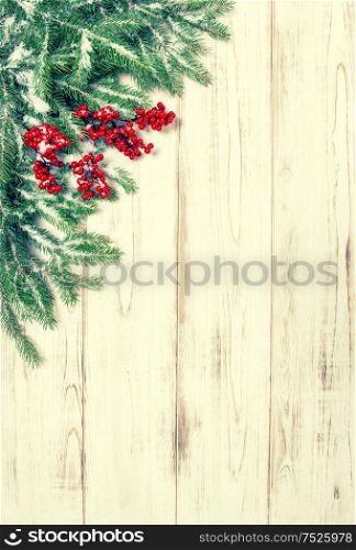 Christmas tree branch with red berries wooden background. Festive decoration. Winter holidays. Vintage style toned picture