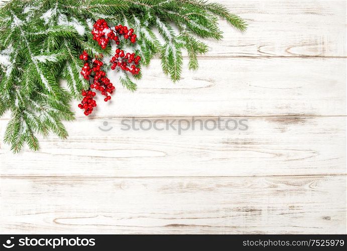 Christmas tree branch with red berries wooden background. Festive decoration. Winter holidays