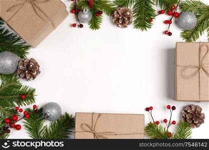 Christmas tree branch with snow , pine cones, red berries and gift boxes on white background with copy space. Christmas gift boxes and decor