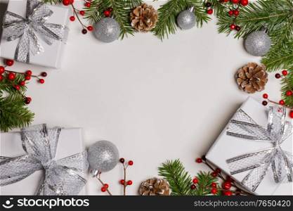 Christmas tree branch with snow , pine cones, red berries and gift boxes on white background with copy space. Christmas gift boxes and decor