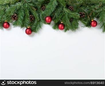 Christmas tree branches and ornaments on white background. Plenty of copy space available.
