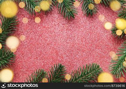 Christmas tree branches on a shiny red background.  Copy space. Bokeh background. 