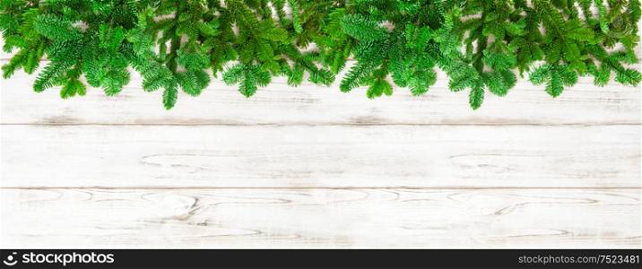 Christmas tree branches on bright wooden background. Holidays banner